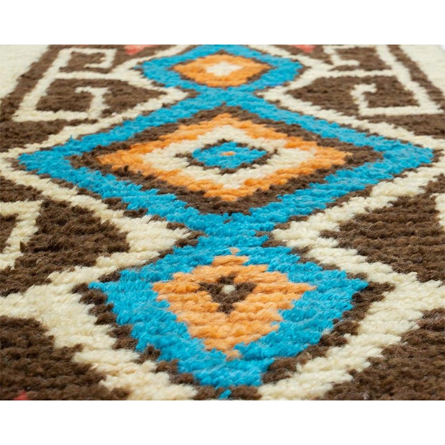 A narrow masterpiece of traditional Moroccan artistry. This hand-knotted wool runner showcases a bold repeating diamond...