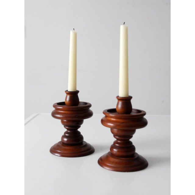 Matched pair of vintage wooden candlestick holders featuring classic turned profiles and warm, natural wood tones. The...