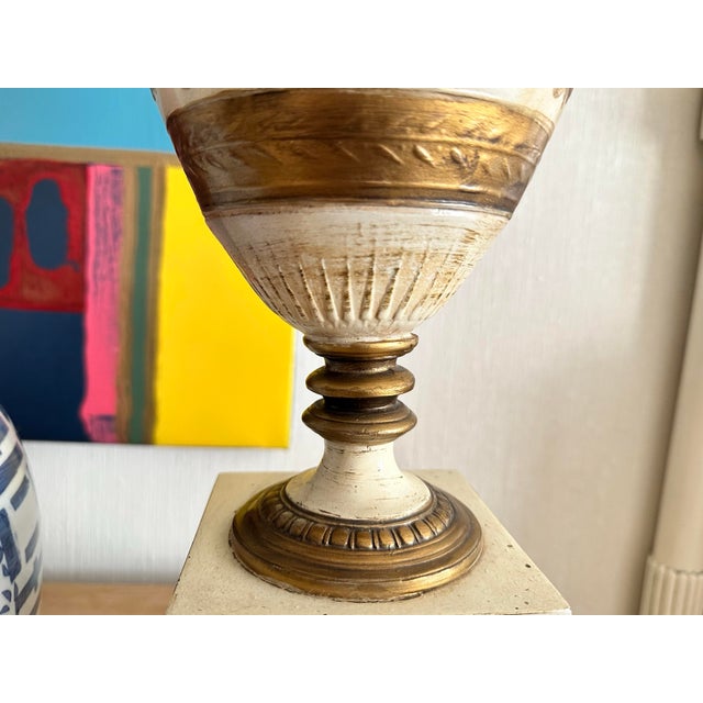 Pair of vintage Grecian themed ceramic lamps with linen shades Lamps are urn shape sitting on a square pedestal base Lamp...