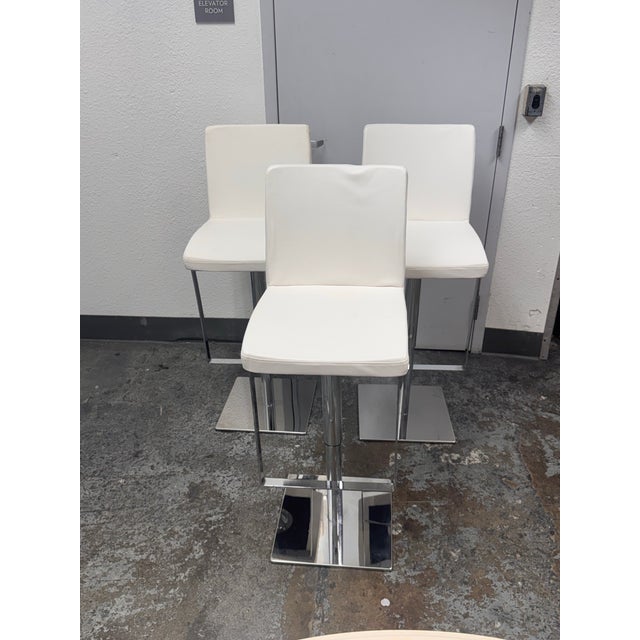 Design Plus Gallery presents Set of Three Contemporary Adjustable Swivel Bar Stools. Each stool is upholstered in white...