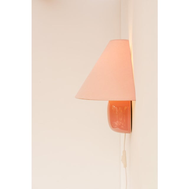 A great and rather large vintage pale pastel pink ikea 80s sconce or wall lighting, which has a round metal fixture with a...