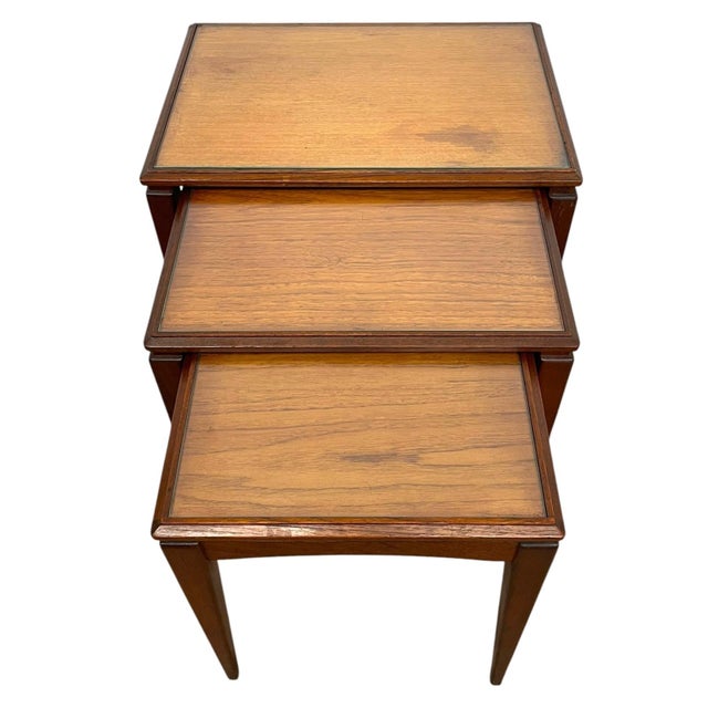 This set of three mid century modern nesting tables features a clean, functional design with tapered legs and warm wood...