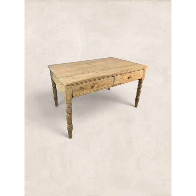 A beautiful antique English pine farmhouse table, circa 1870, with a warm scrubbed finish, two front drawers, and classic...
