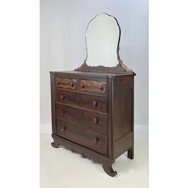 American Empire period dresser with mirror. Constructed with beautiful flame mahogany veneers, the dresser features a...