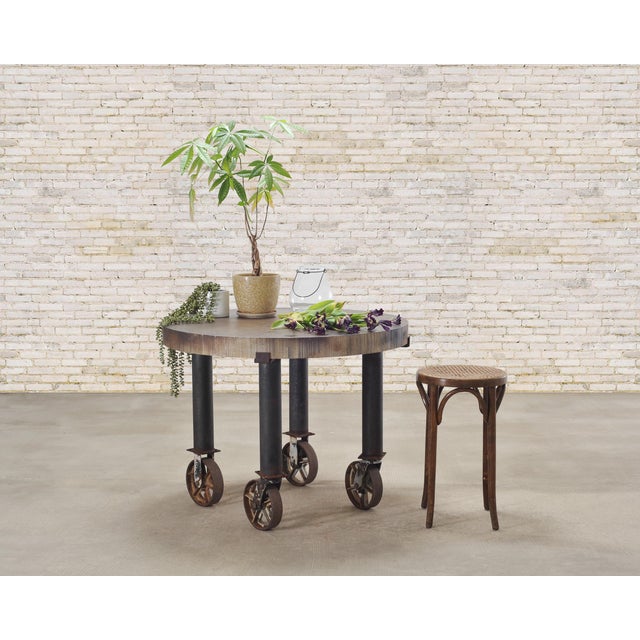 A large imposing American industrial machined steel and iron work table supported by oversized casters. The table features...
