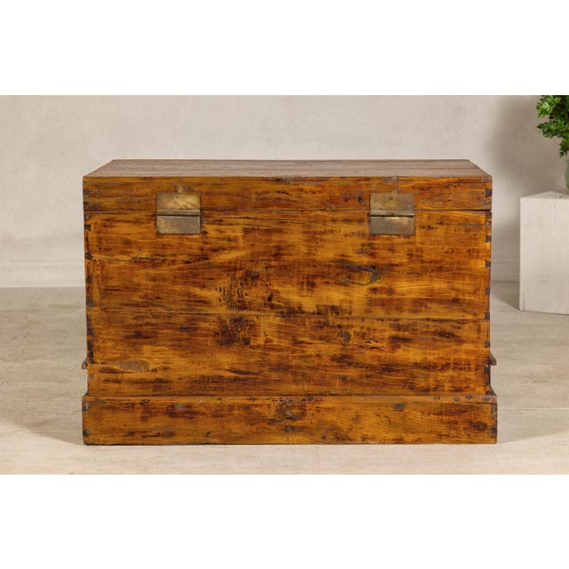 A late Qing Dynasty elm blanket chest with dovetail accents and discreet red carved motifs. This antique Chinese elm...