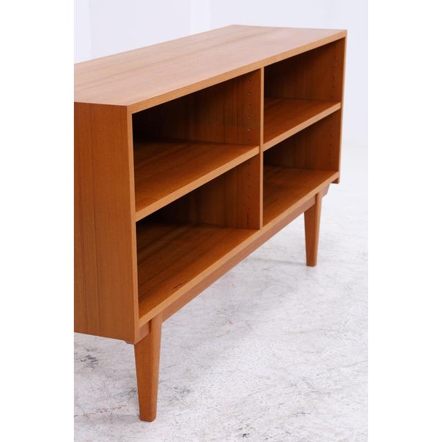Vintage teak shelving unit with four spacious open compartments and a clean, straight design. The compact frame stands on...