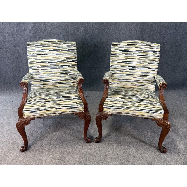 This pair of Baker Furniture Stately Homes Gainsborough arm chairs features beautifully carved wood frames with elegant...