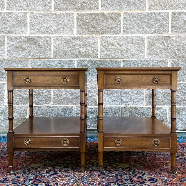 A pair of vintage Hekman Traditional Regency style tiered side tables in medium walnut, each having two dovetailed drawers...