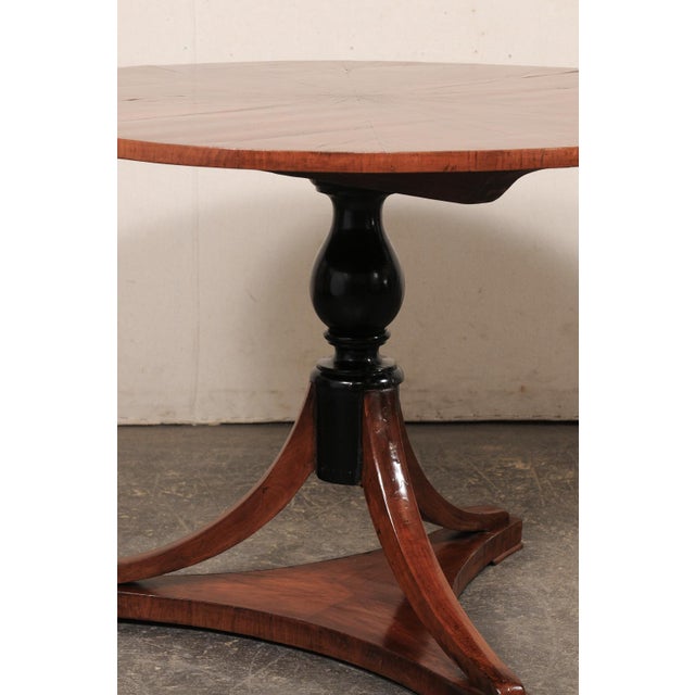 An Italian wooden pedestal table from the 19th century. This antique center table from Italy has a round-shaped top, with...