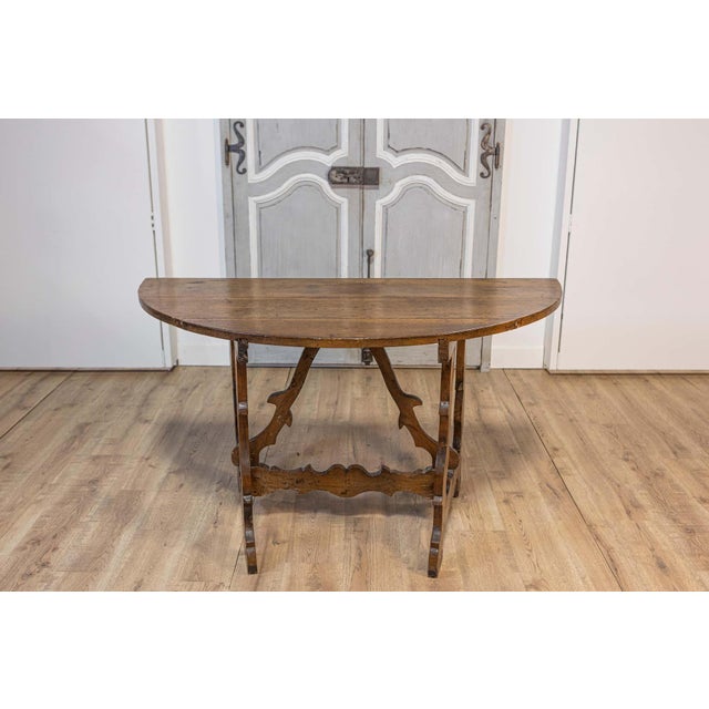 An Italian Baroque period walnut console table from the 17th century with carved lyre-shaped base. This Italian Baroque...