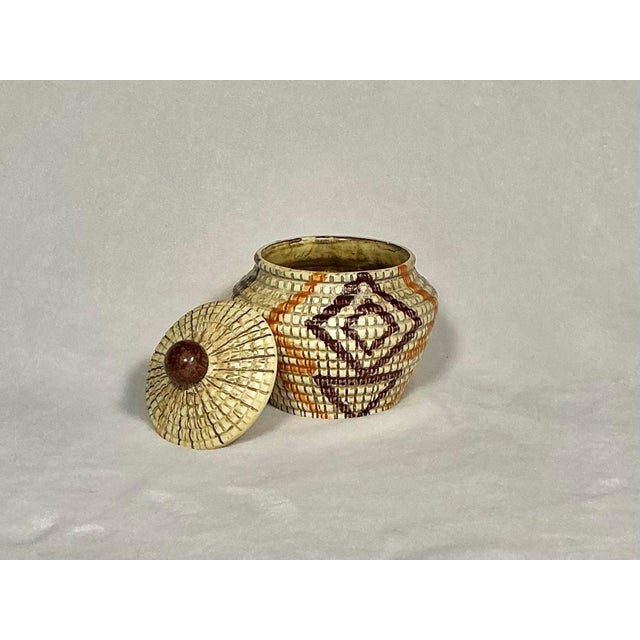 Vintage, Mid-Century lidded ceramic jar features a textured, basket-weave surface with hand-painted geometric Native...