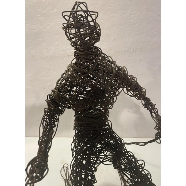 A striking vintage wire sculpture depicting a downhill skier captured in motion. Hand-formed from continuous dark metal...