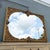 An exceptional vintage Rococo-style wall mirror featuring an intricately carved solid wood frame finished in rich antiqued...