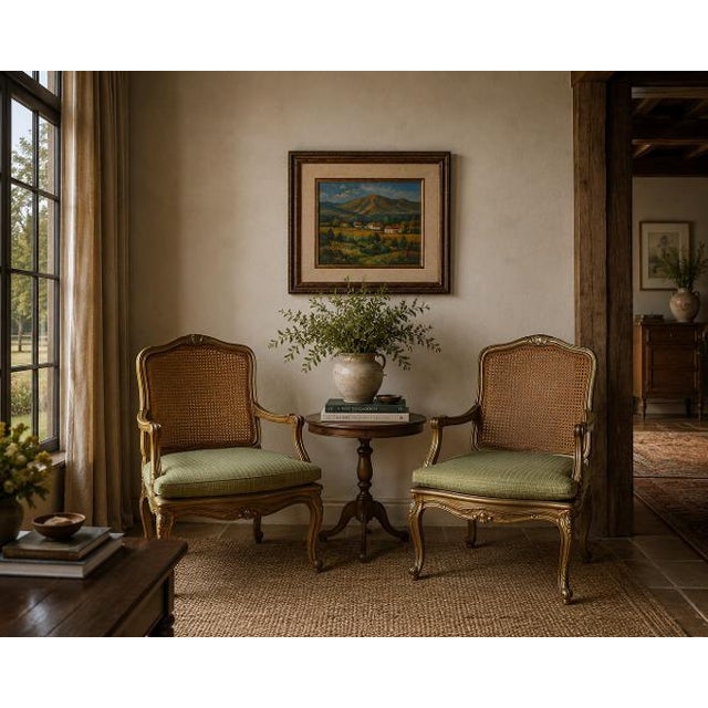 Elegant pair of vintage Hollywood Regency armchairs designed in the French Louis XV style. Each chair features a...