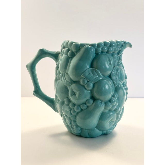 Beautiful ceramic serving pitcher set, with a fruit relief pattern throughout. The ceramic is in a celadon color and a...