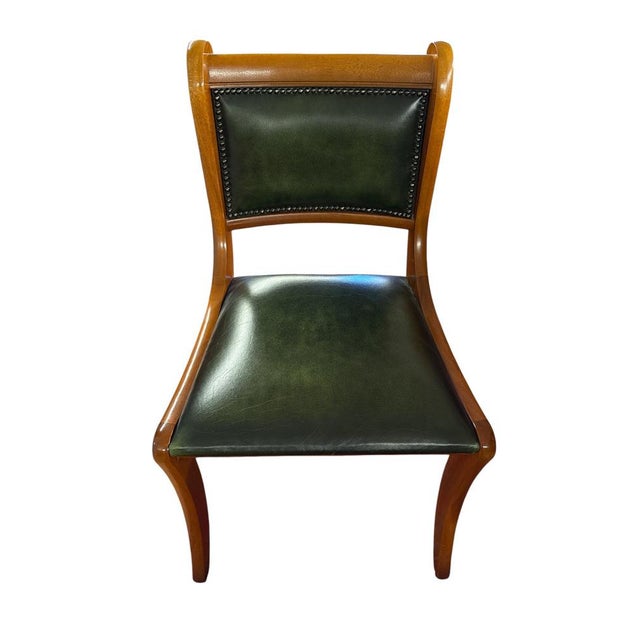 Classic English chair with a solid wood frame and deep green leather seat and back, finished with brass nailhead trim....