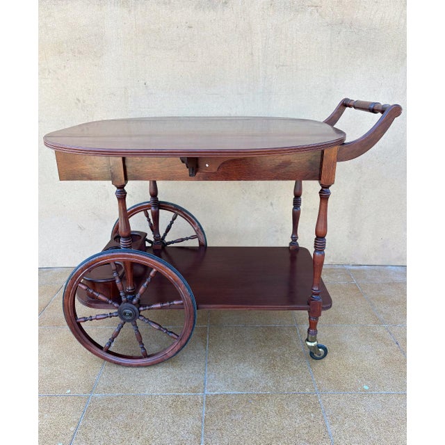 Elegant vintage tea and bar cart crafted in rich mahogany, dating from the 1940s. This refined serving trolley features...
