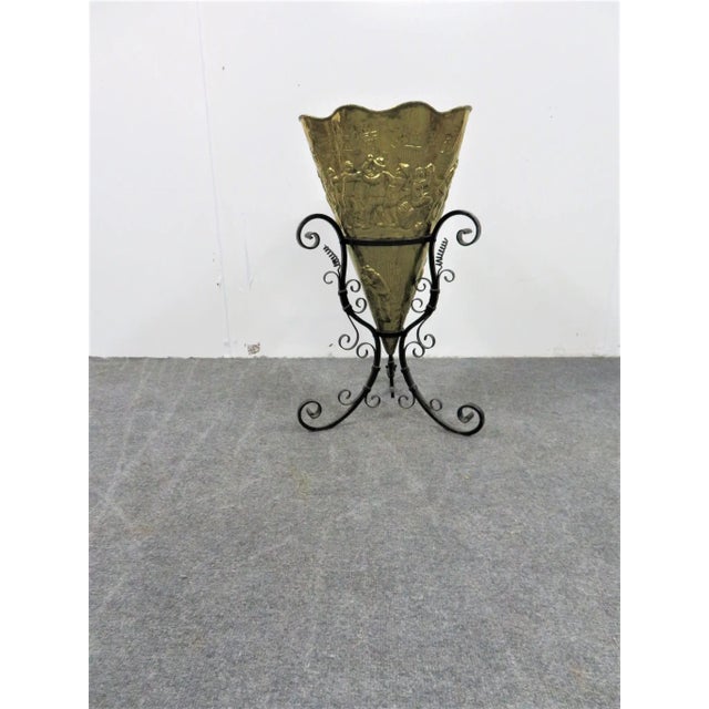 This is an umbrella holder from the early 20th century. The piece features a brass insert with an embossed pub scene. The...