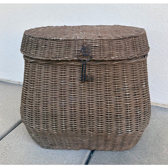 The pot-belly shape, inset side handles, and front latch mechanism of this vintage basket mimic the silhouette of a...