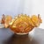 A luminous vintage marigold carnival glass bowl featuring a bold geometric sunburst pattern and scalloped edges. Its...