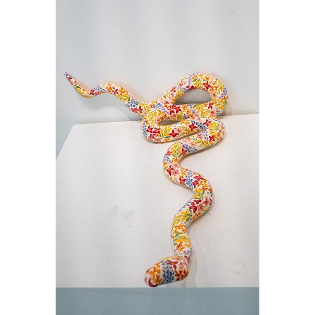 A whimsical snake sculpture by American artist Paige Barnes Dorsey. Featuring hand painted florals, this smooth textured...