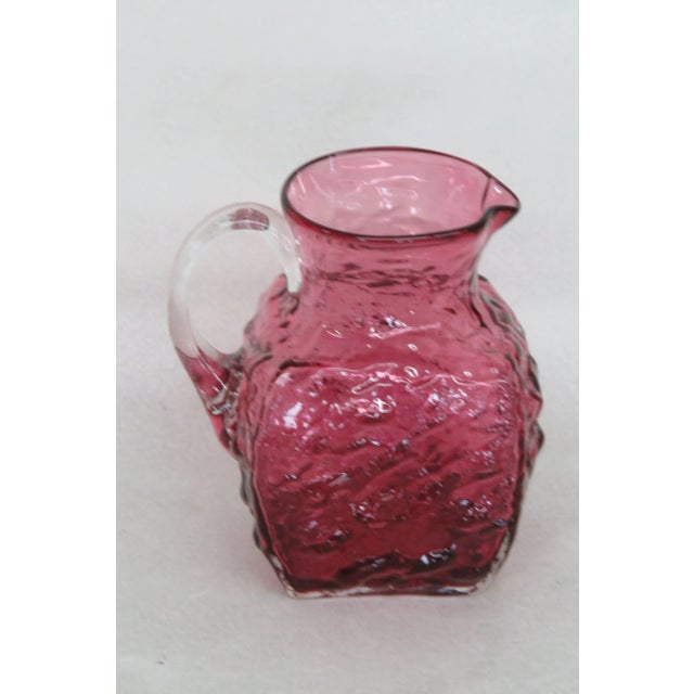 This gorgeous pitcher is made of glass. This small pitcher is made in a lovely cranberry / dark pink color with a clear...