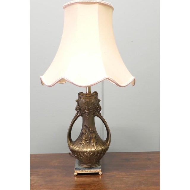 This is a very attractive and large lamp the two handled base is made in brass, it is decorated with dancing children. The...
