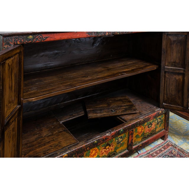 Painted Tibetan cabinet with hidden storage in base.