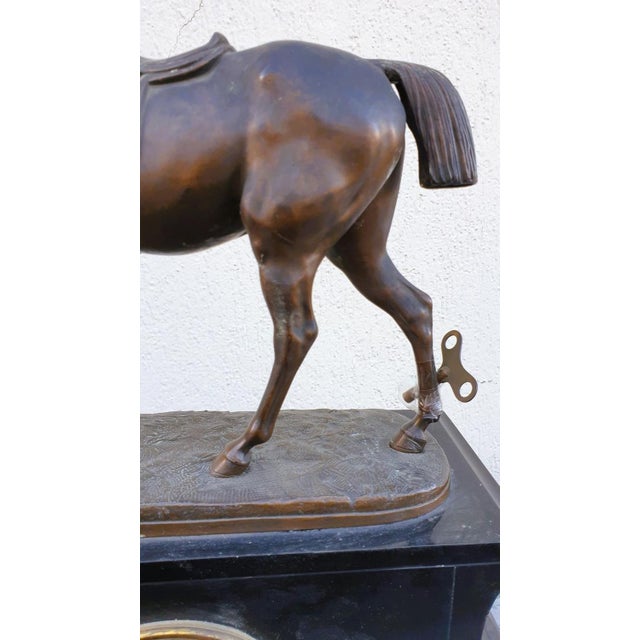 Black marble clock, surmounted by a horse in spelter with brown bronze-like patina, signed Emile Loiseau Some chips to the...
