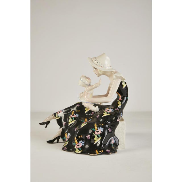 Polychrome sculpture depicting a mother with a baby in terracotta collage. Manufacturer's mark on the base. Production...