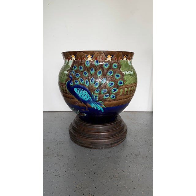 Eye catching large enamel painted peacock planter turned into decorative table, with a glass top and wood base. Sold as a...