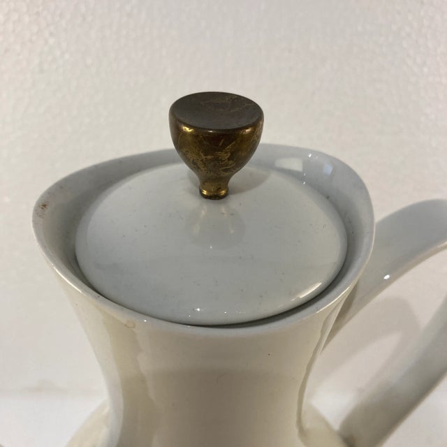 Porcelain coffee or tea pot. Off-white with a brass a detail.