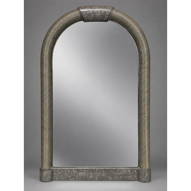 The mirror is distinguished by its rounded arch form, ribbed rope-like side members, and block-like gray tessellated stone...
