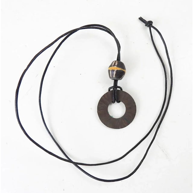 Vintage 1990's artist studio hammered bronze circle with glass trade bead accent. On thin round black leather cord,...