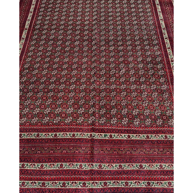 The field of this hand-knotted Afghan Turkmen rug is nearly black — a very deep midnight navy — filled wall to wall with...