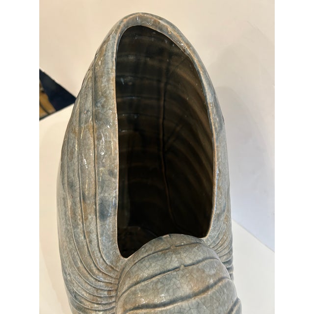 Striking large ceramic sculpture in the shape of a nautilus shell in a neutral shade of grey.