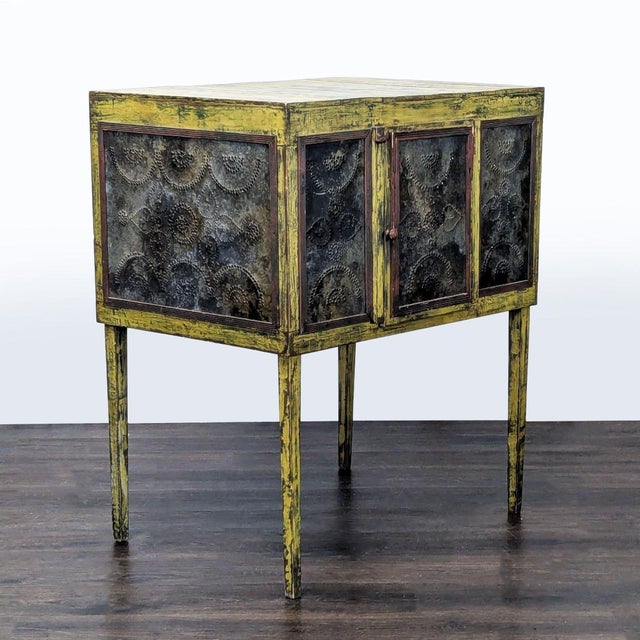 This cabinet features a distressed yellow finish and unique metal-paneled doors with perforated floral patterns. The...