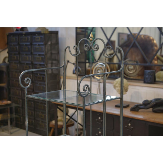 An elegant wrought iron shelf, typical of the 1950s, with an airy and graphic design. The metal frame is crafted with...