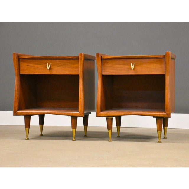 A pair mid century modern walnut nightstands by Kent Coffey The Sharon with brass capped leg ferrules and a single drawer....