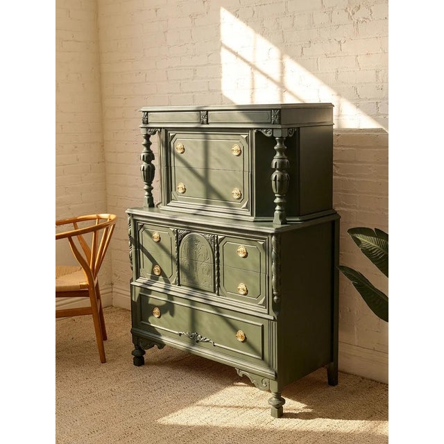 A dramatic antique highboy dresser finished in a deep hunter green, with an architectural silhouette and an abundance of...