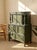A dramatic antique highboy dresser finished in a deep hunter green, with an architectural silhouette and an abundance of...