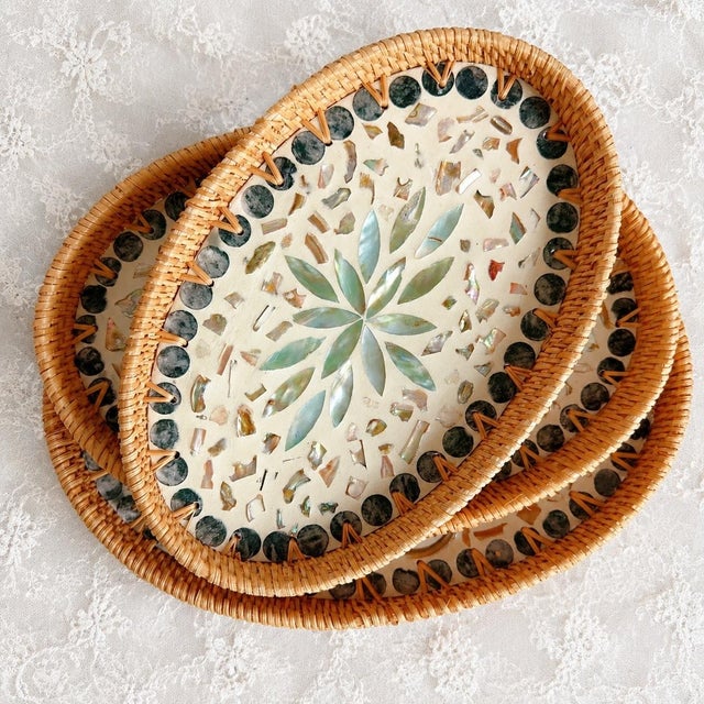 Set of three oval decorative trays with hand-woven edges made of natural rattan and mother-of-pearl inlay on the surface....