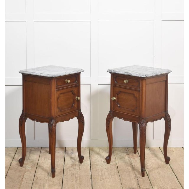 Pair of walnut bedside cabinets, the square well-figured marble tops with rounded corners over a single short drawer with...
