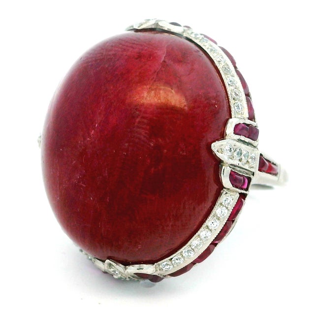 A dramatic vintage statement ring centered by an impressive cabochon ruby of exceptional scale, displaying a deep,...