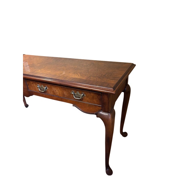 Elegant vintage Queen Anne–style console table featuring richly figured burl wood veneer in a warm medium-brown finish....