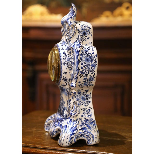 This ornate French mantel clock was crafted circa 1860 in the Delft style, featuring hand-painted blue and white faience...