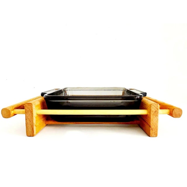 Offered is a vintage 1970s Oak wood cradle/rack that has been paired with a black Anchor Hocking tempered glass casserole...