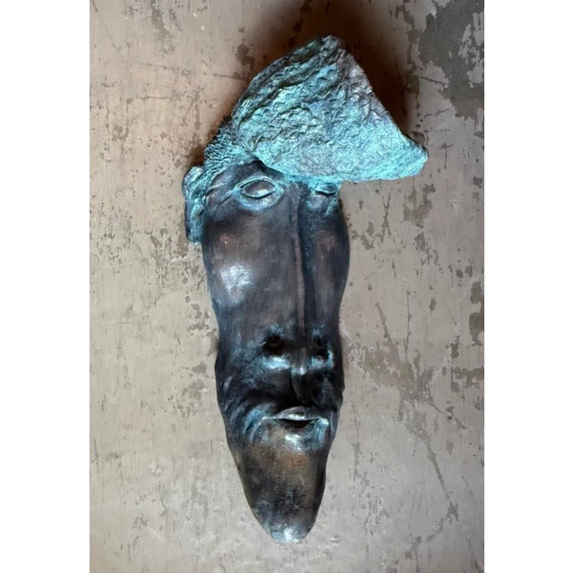 A powerful work of sculptural art, this vintage bronze wall mask commands attention with its serene, contemplative...