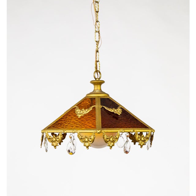 An antique pendant light with 6 rippled, stained glass panes forming a coolie shape; alternating between amber and red-...